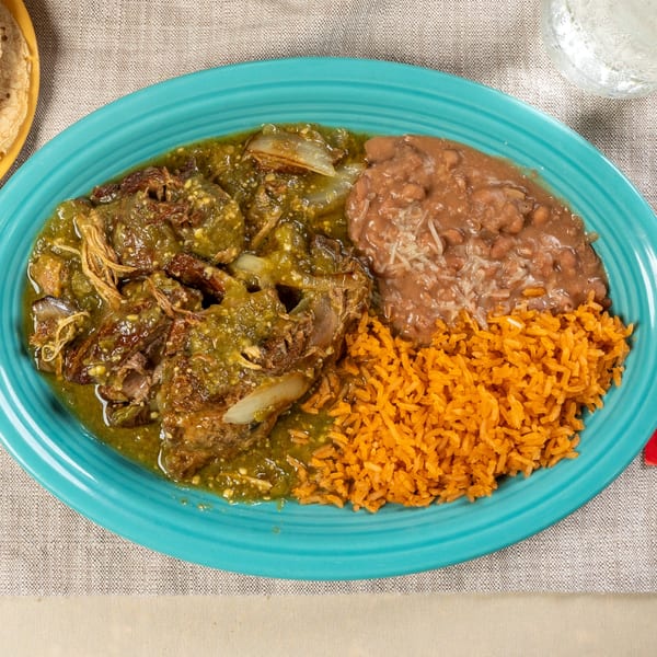 Chavela's Mexican Cuisine's pork in green sauce with rice and refried beans on a blue plate.