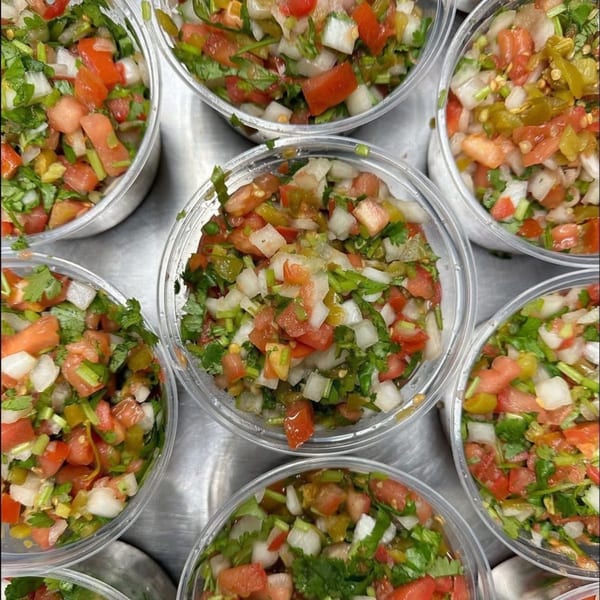 Multiple clear plastic containers filled with fresh pico de gallo, featuring diced tomatoes, onions, and cilantro.