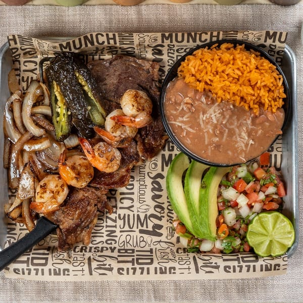 Chavela's Mexican Cuisine platter with steak, shrimp, grilled onions, peppers, rice, beans, avocado, and pico de gallo.